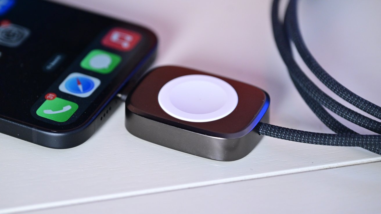 An iPhone with an Apple Watch charger plugged in