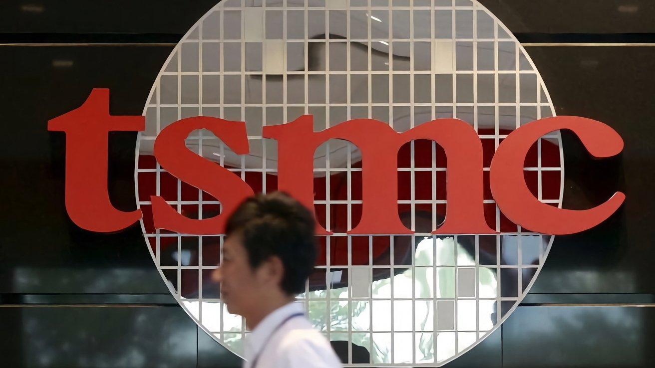 Large red TSMC logo on a grid-patterned circular background, with a person walking by in the foreground.