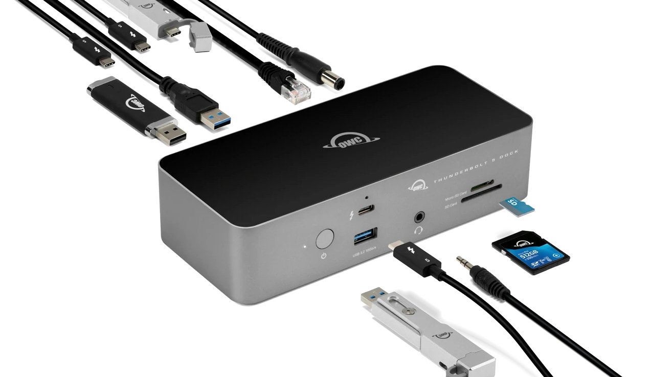 Silver Thunderbolt dock with various connected cables and devices, including USB, HDMI, and SD cards, arranged around it for connectivity illustration.